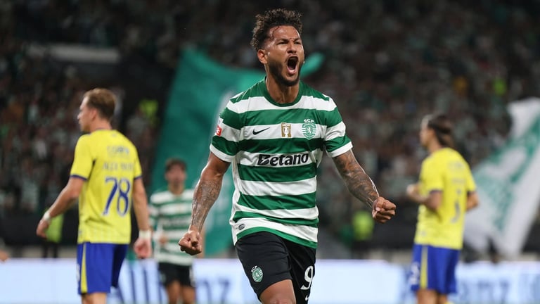 Soccer player in green and white striped jersey celebrating with fist raised during match against team in yellow
